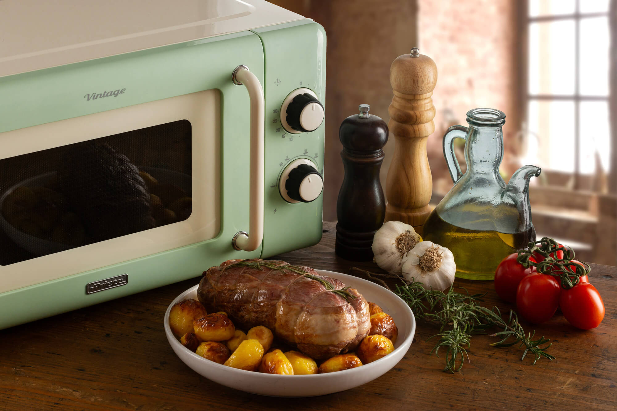 Zielona kuchenka mikrofalowa w stylu vintage. Pieczeń, pomidory, czosnek, olej i przyprawy na stole.