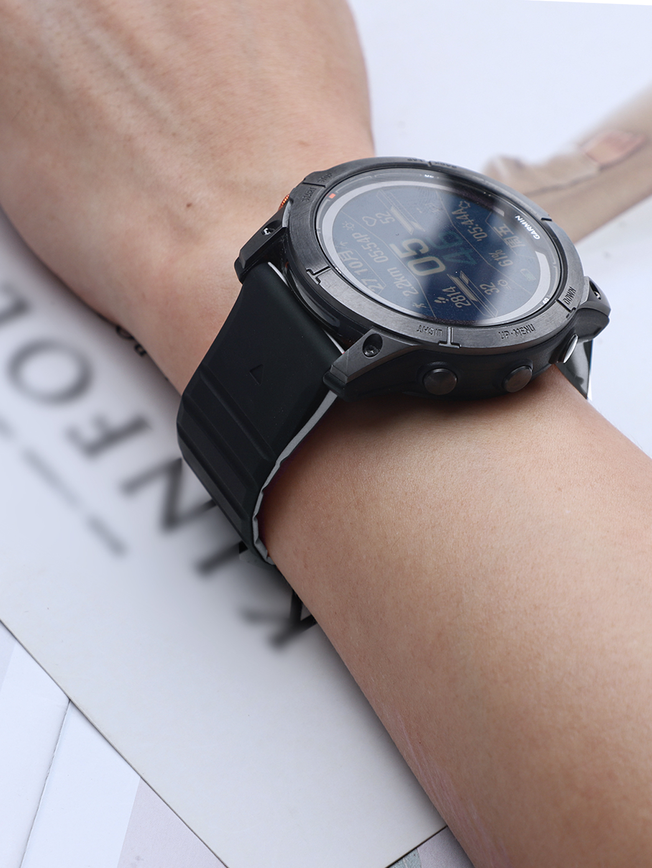 Smartwatch am Handgelenk, schwarzes Armband, heller Hintergrund.