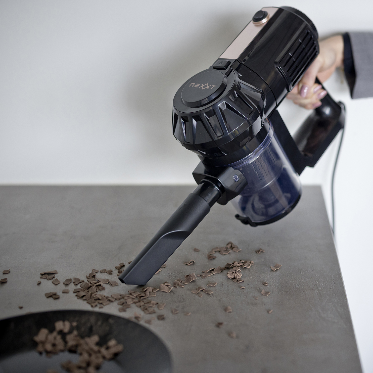 A person using a black and copper vacuum cleaner to clean up crumbs.