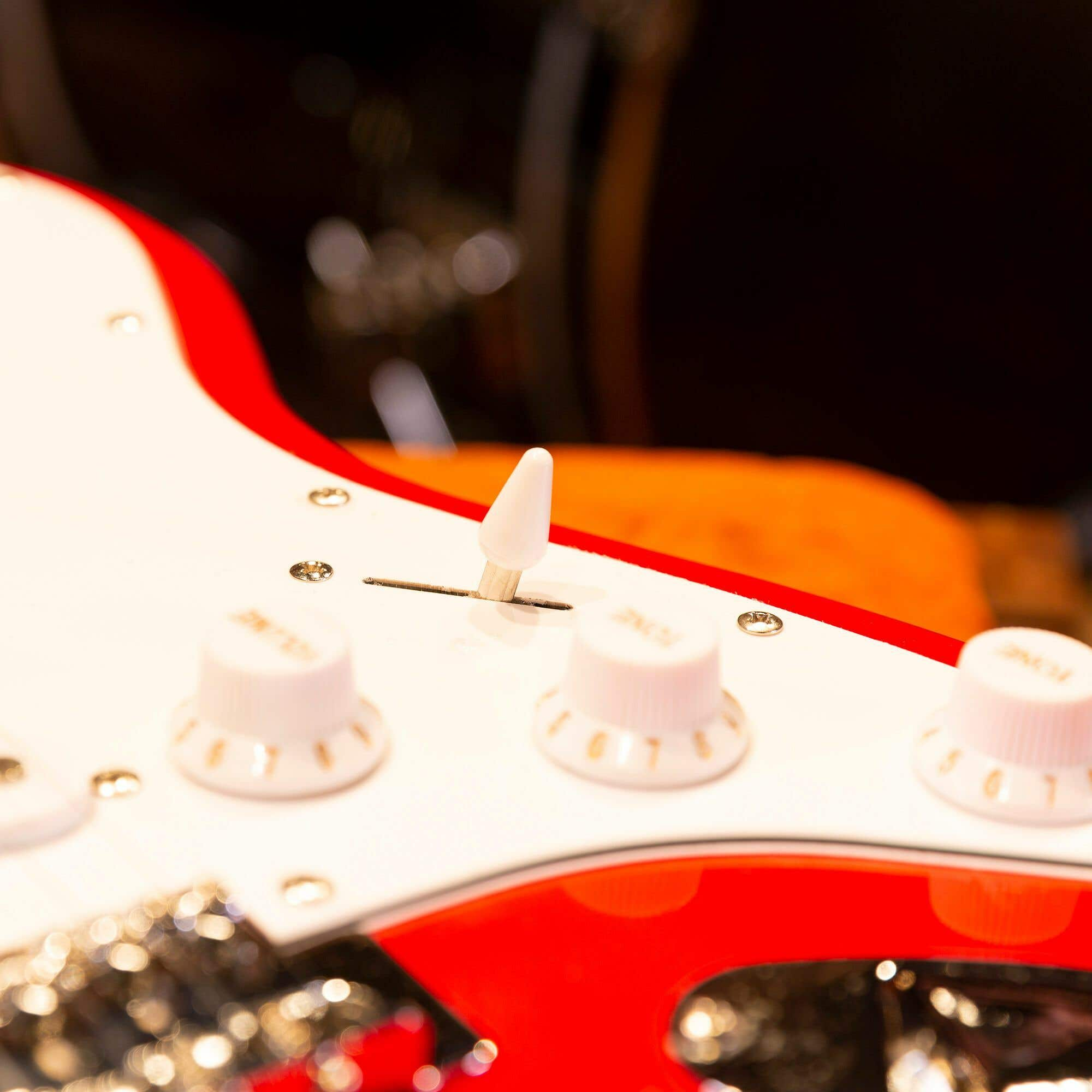 Gros plan sur les boutons de volume et de tonalité sur le corps d'une guitare électrique rouge.