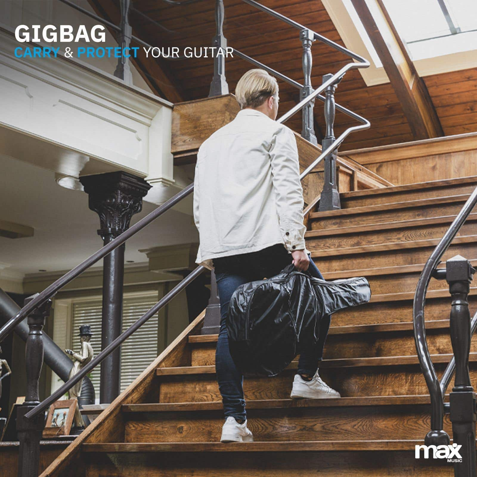 Ein Mann in einer weißen Jacke trägt einen Gitarrenkoffer eine Holztreppe hinauf.