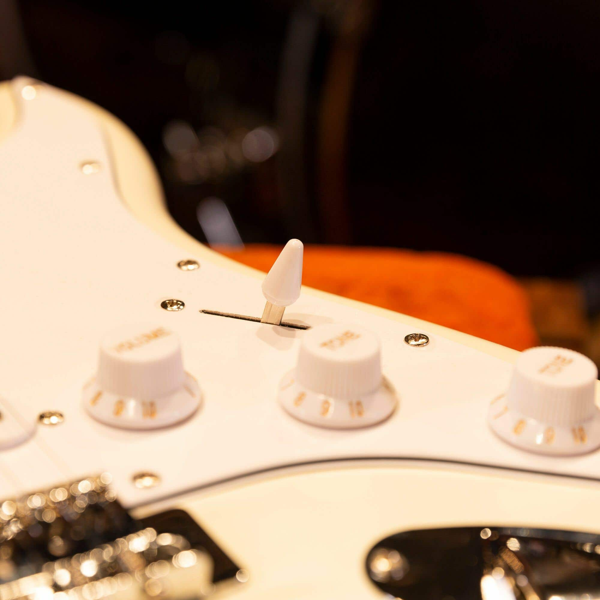 Nahaufnahme der Gitarrenbedienelemente. Weiße Knöpfe, ein Schalter und die weiße Oberfläche.