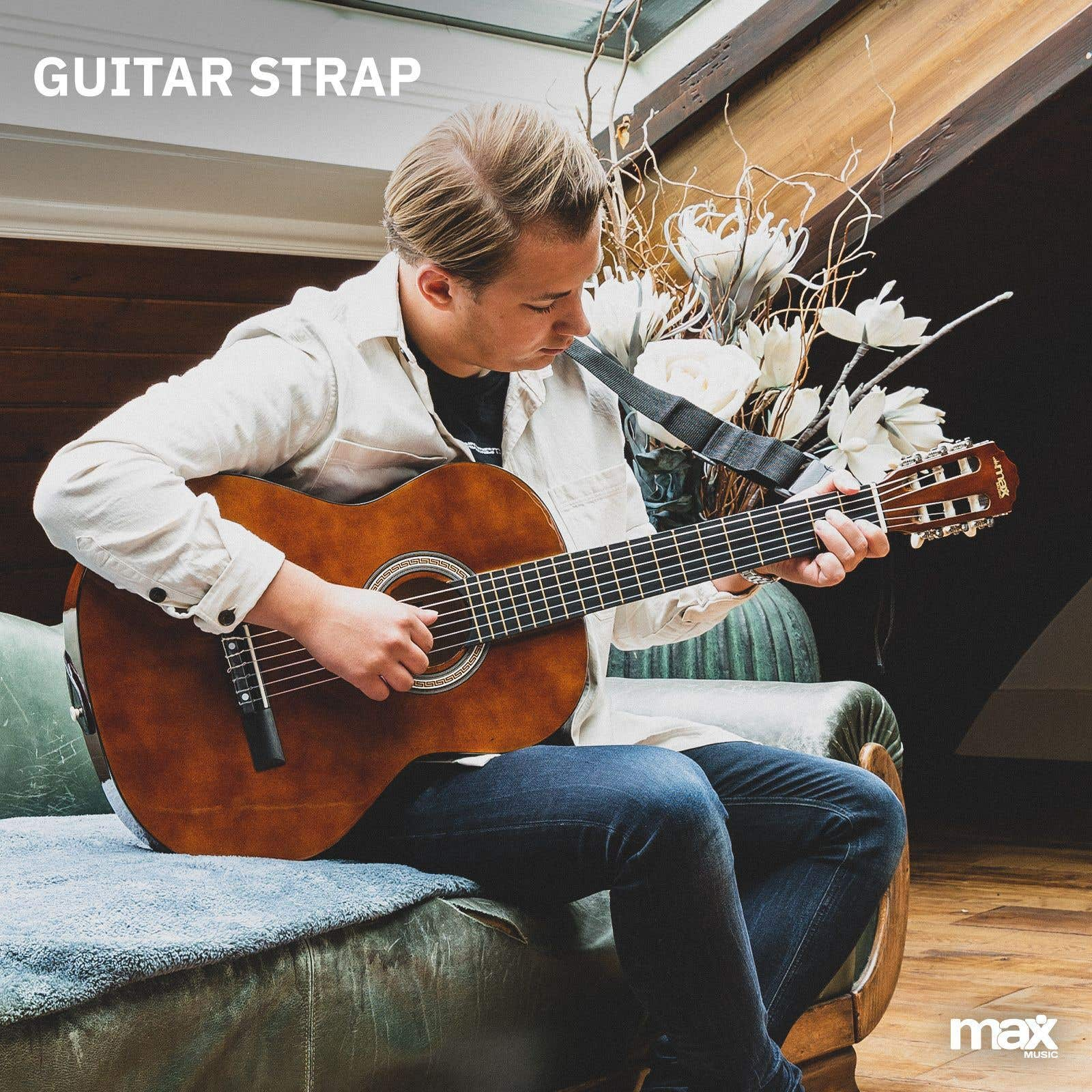 Mann spielt Akustikgitarre, sitzt auf grünem Sofa.