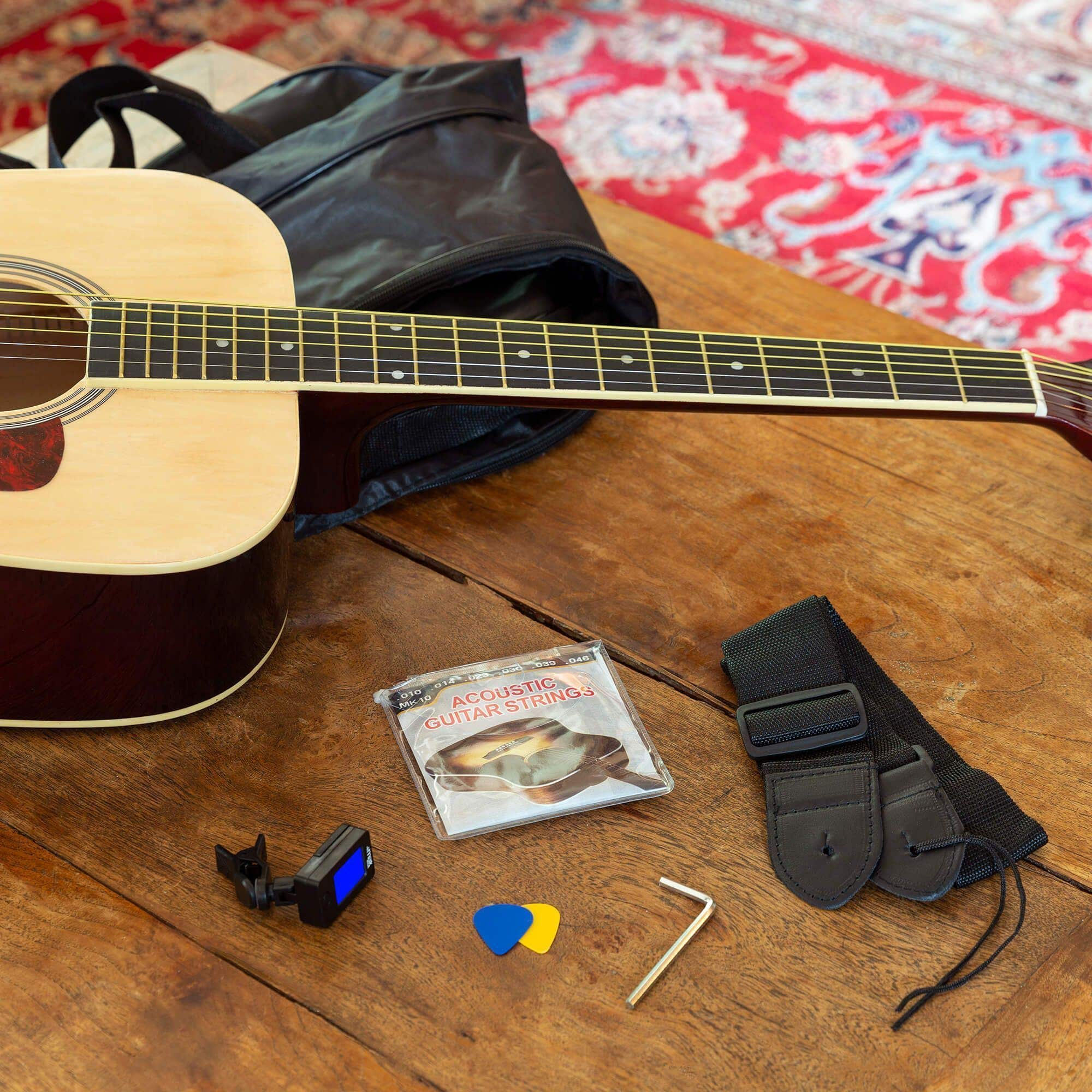 Akoestische gitaar met accessoires op houten tafel. Gitaarsnaren, plectrums, tuner, band.