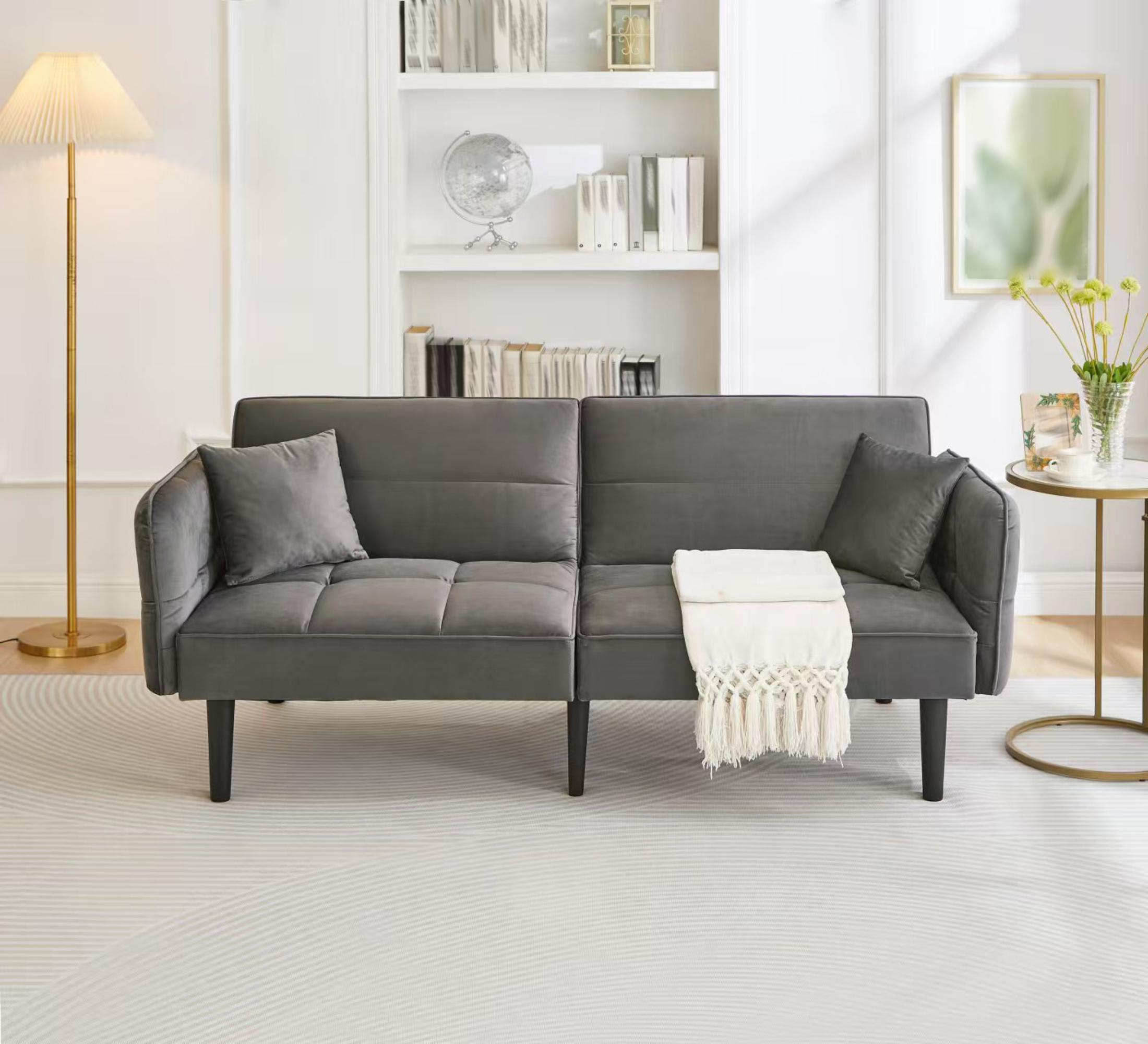 Graues Sofa mit Kissen, einer weißen Decke und einer Lampe in einem Wohnzimmer. Bücherregal und Dekoration im Hintergrund.