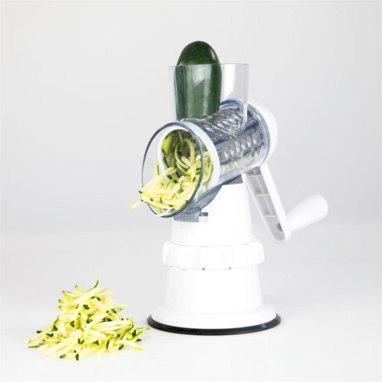 Ein weißer Gemüseschneider in Gebrauch, der Zucchini in Julienne-Streifen schneidet, mit einem Haufen geschnittener Zucchini.