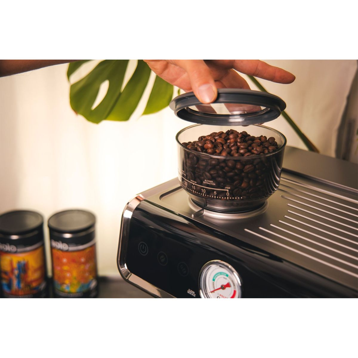 Person fügt Kaffeebohnen in einen Behälter auf einer Espressomaschine hinzu.