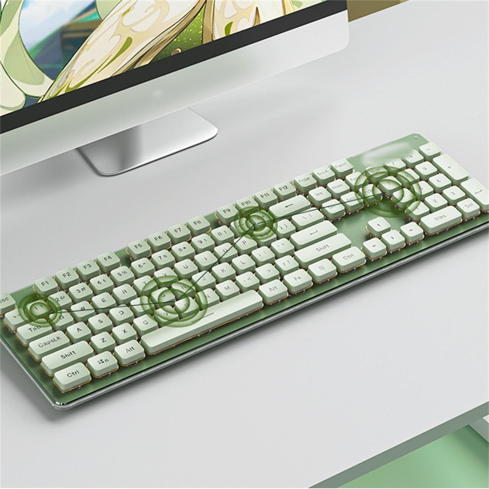 Grüne Tastatur auf einem Schreibtisch. Ein Computermonitor im Hintergrund. Grüne Tastatur mit weißen Tasten.