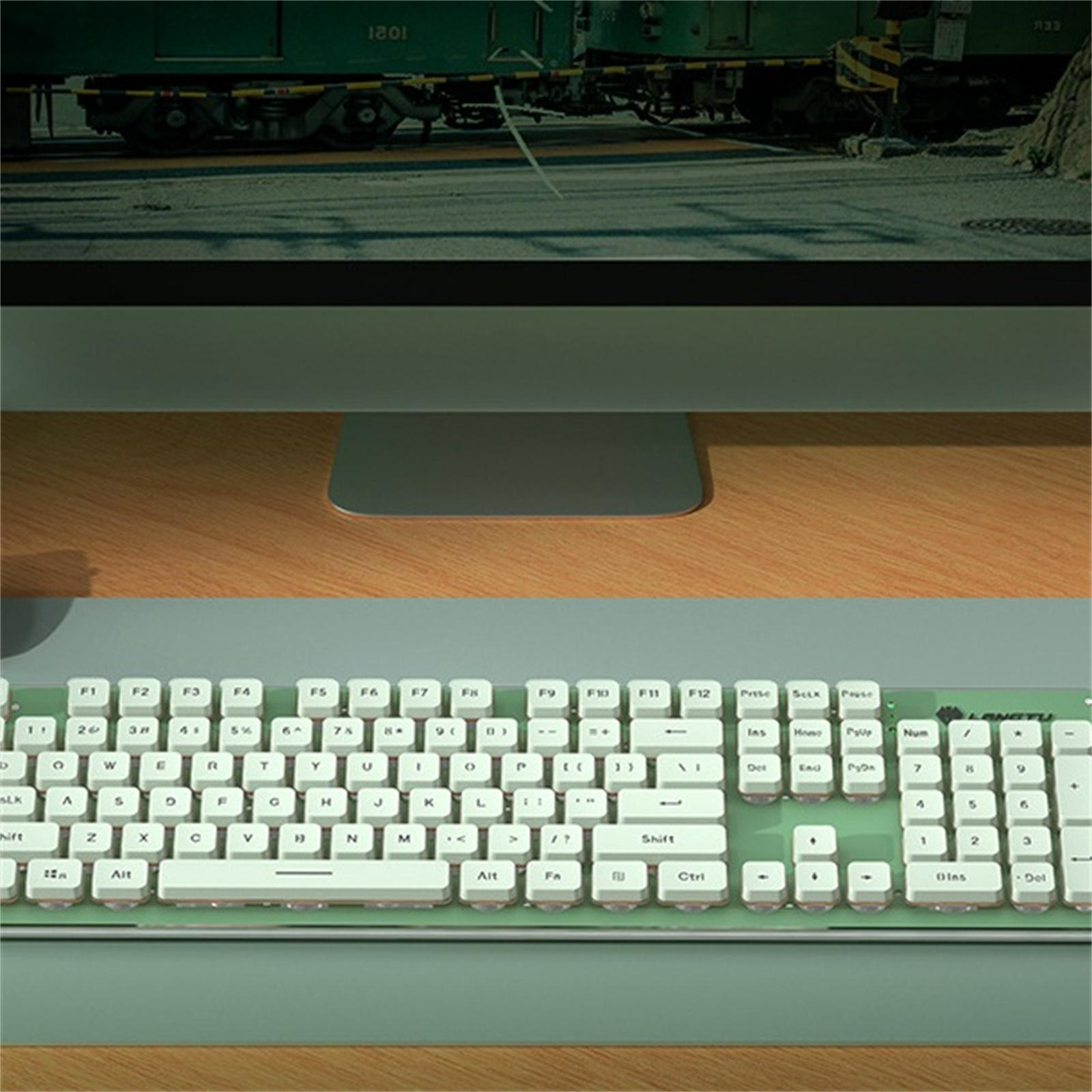Weiß-grüne mechanische Tastatur mit Monitor und Holzschreibtisch im Hintergrund.