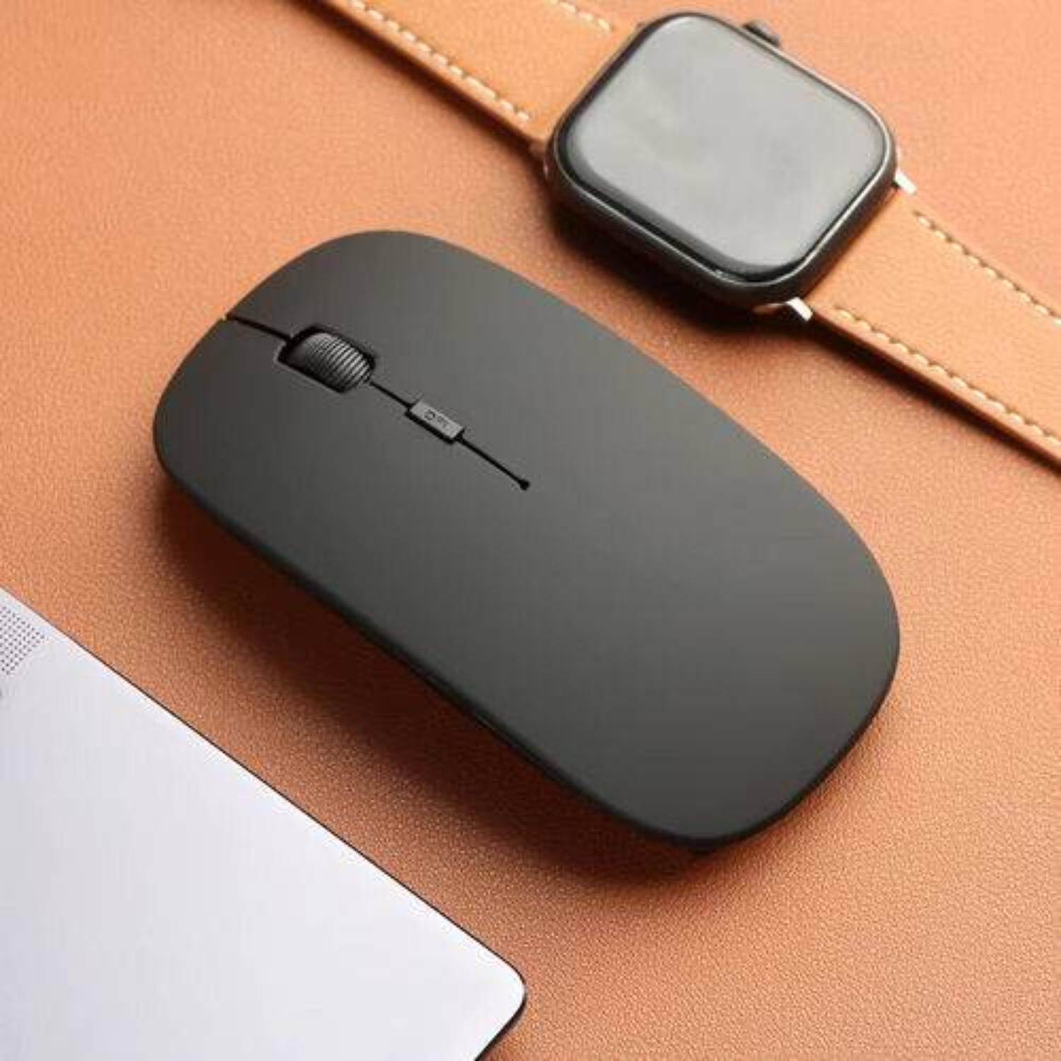 Schwarze Maus neben einer Uhr und Laptopkante, auf brauner Oberfläche. Draufsicht.
