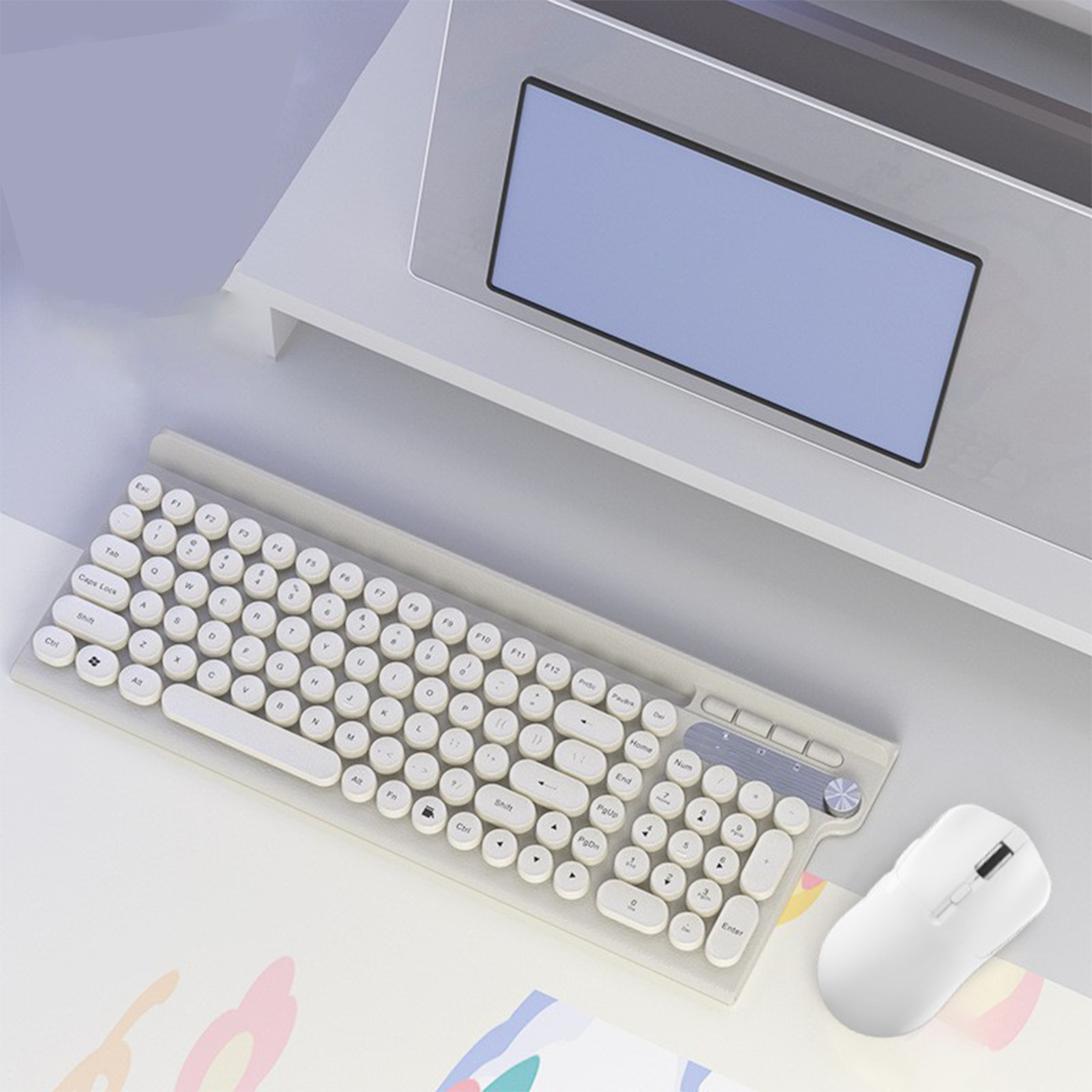 Tastatur und Maus auf einem Schreibtisch. Die Tastatur ist grau mit runden Tasten. Laptop im Hintergrund.