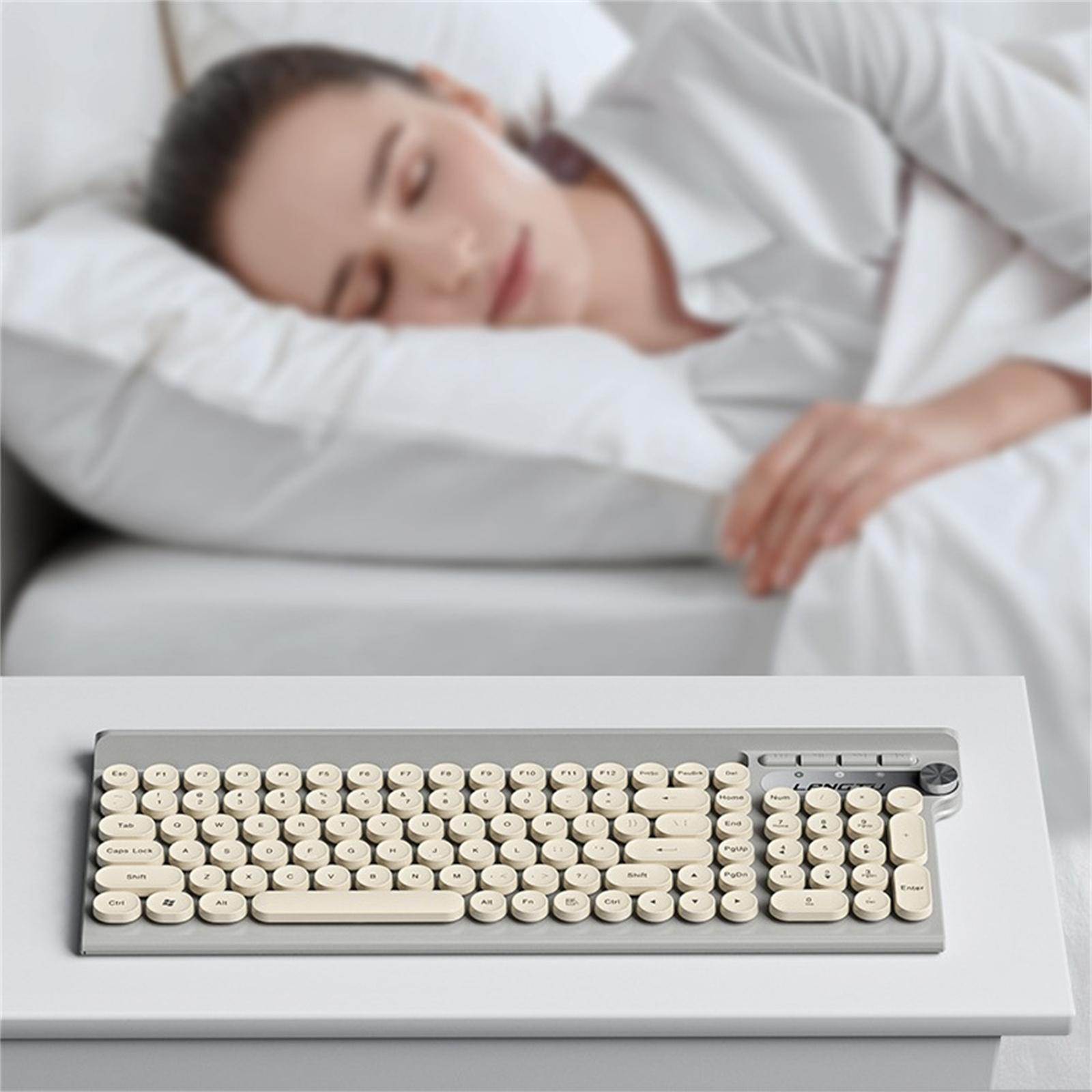 Eine Frau schläft in einem Bett. Eine graue Tastatur steht auf dem Tisch vor dem Bett.