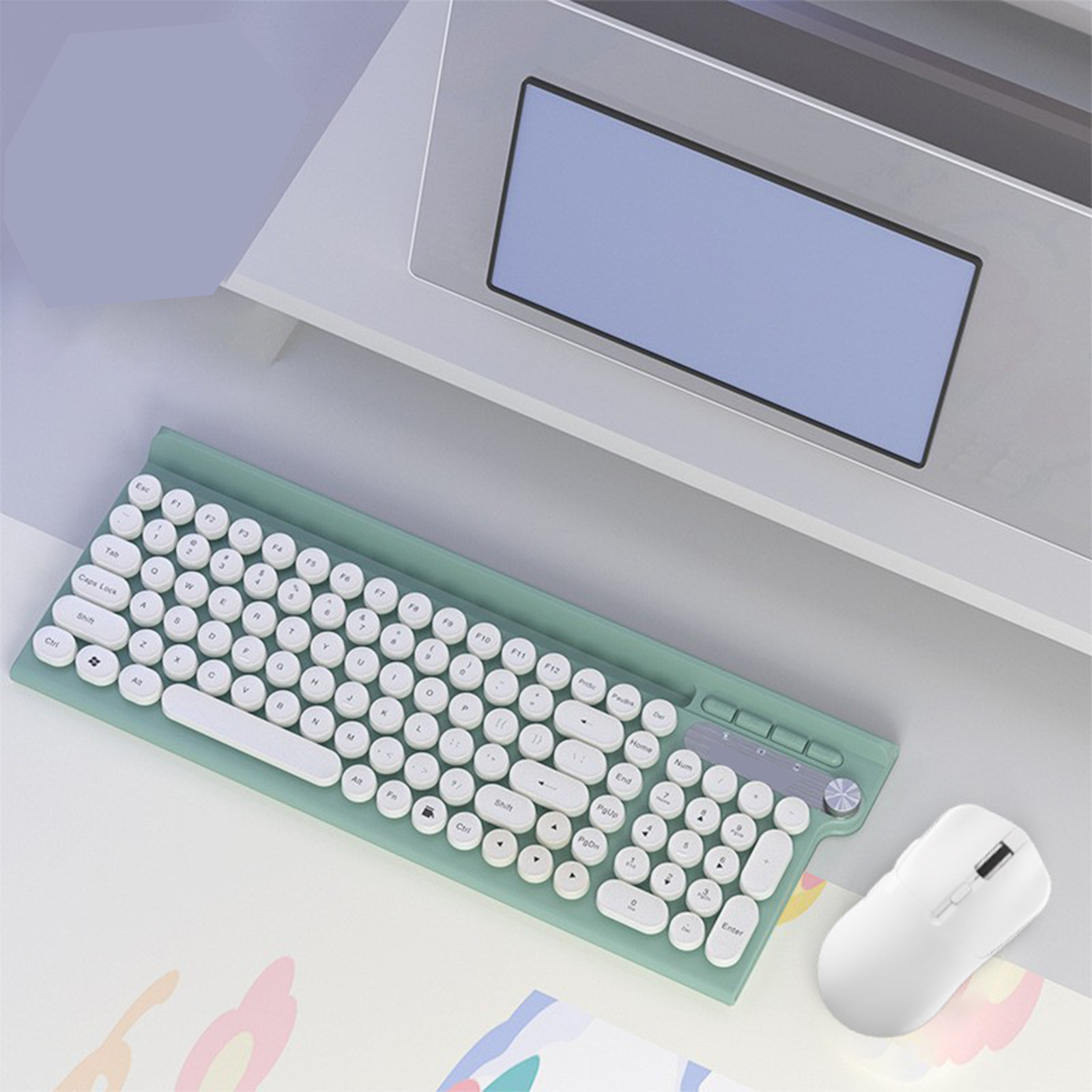 Grüne Tastatur und Maus auf einem Schreibtisch. Die Tastatur hat runde Tasten. Laptop im Hintergrund.