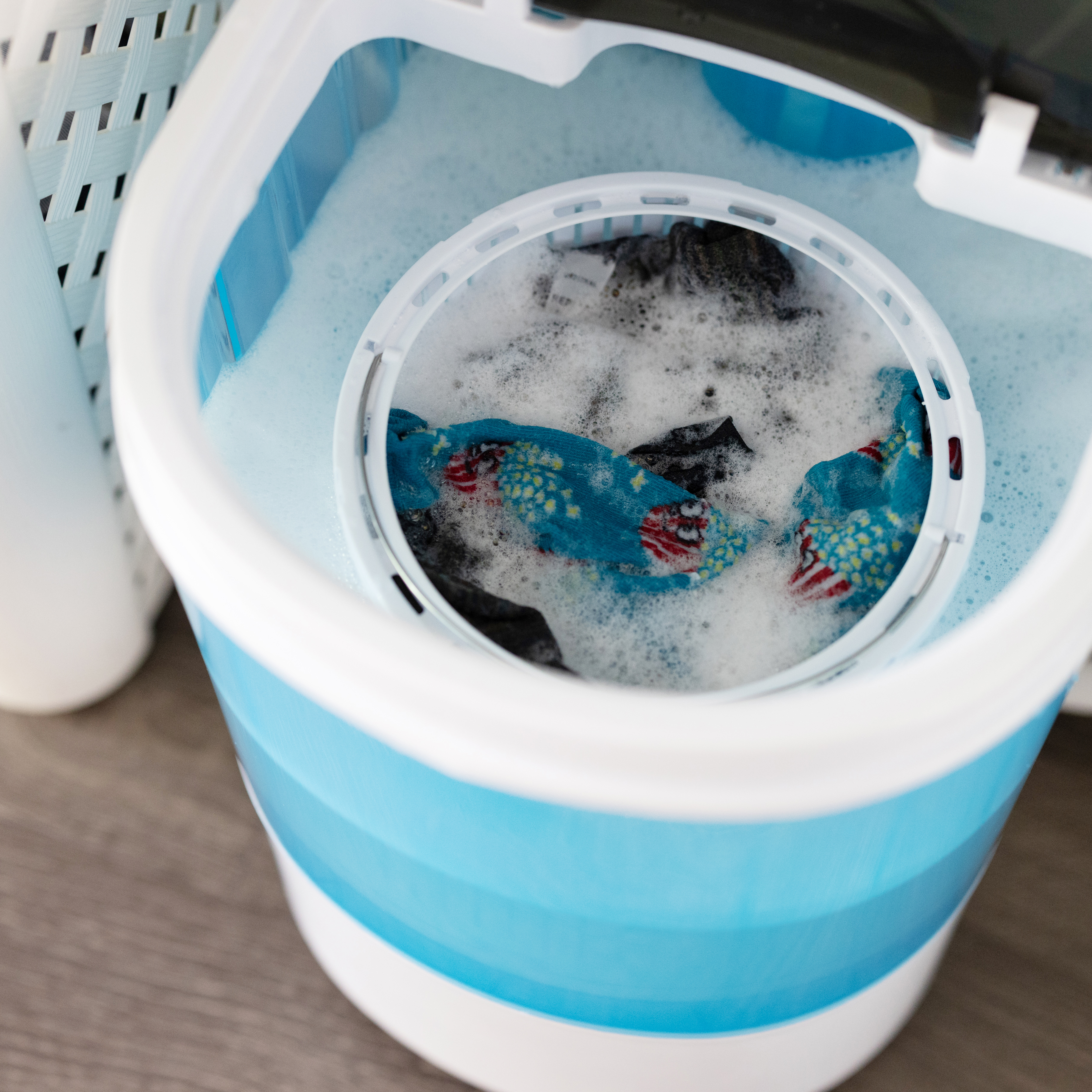 Close up of a washing machine drum with clothes inside. Foamy water fills the drum.