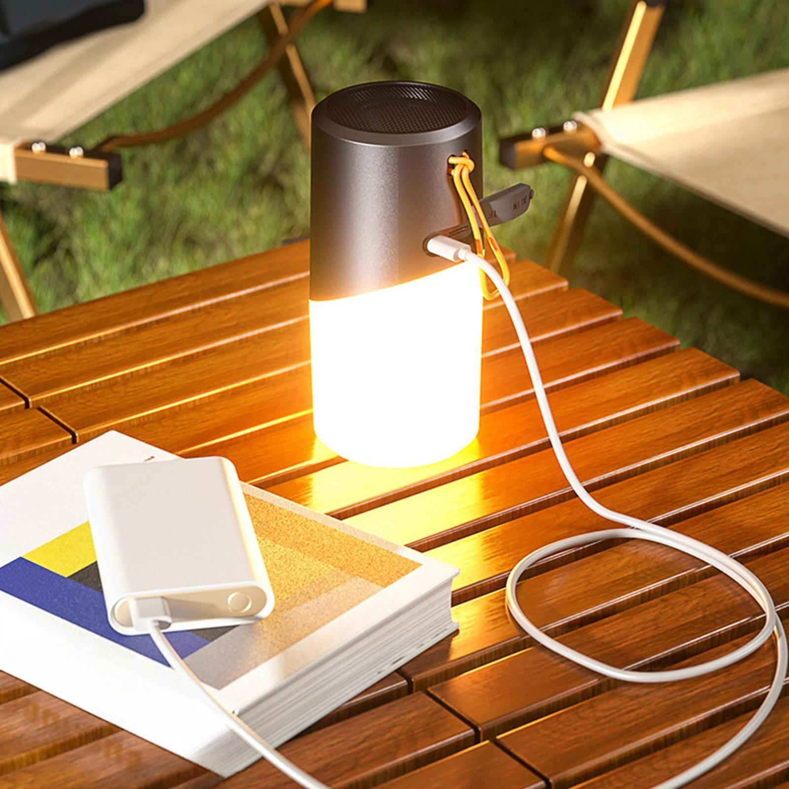 Eine leuchtende Lampe auf einem Holztisch, neben einem Buch und einer Powerbank. Ein Ladekabel ist angeschlossen.