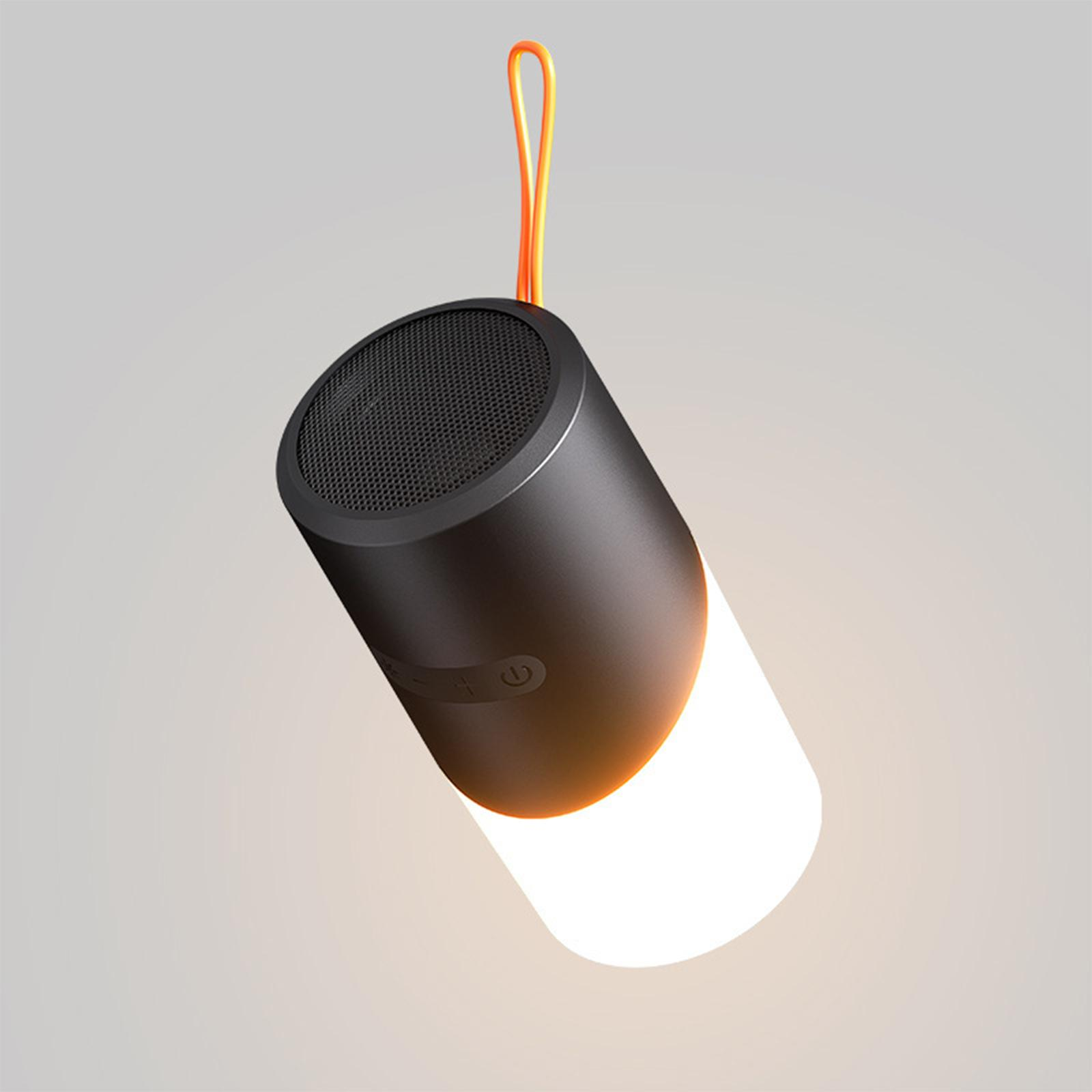Ein schwarzer Lautsprecher mit weißem Licht am Boden, hängend an einem orangefarbenen Kabel.