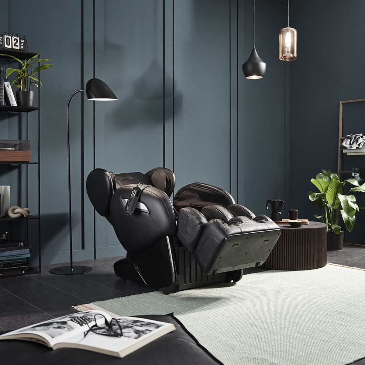 Schwarzer Massagesessel, schwarze Stehlampe und dunkle Wand in modernem Wohnzimmer.