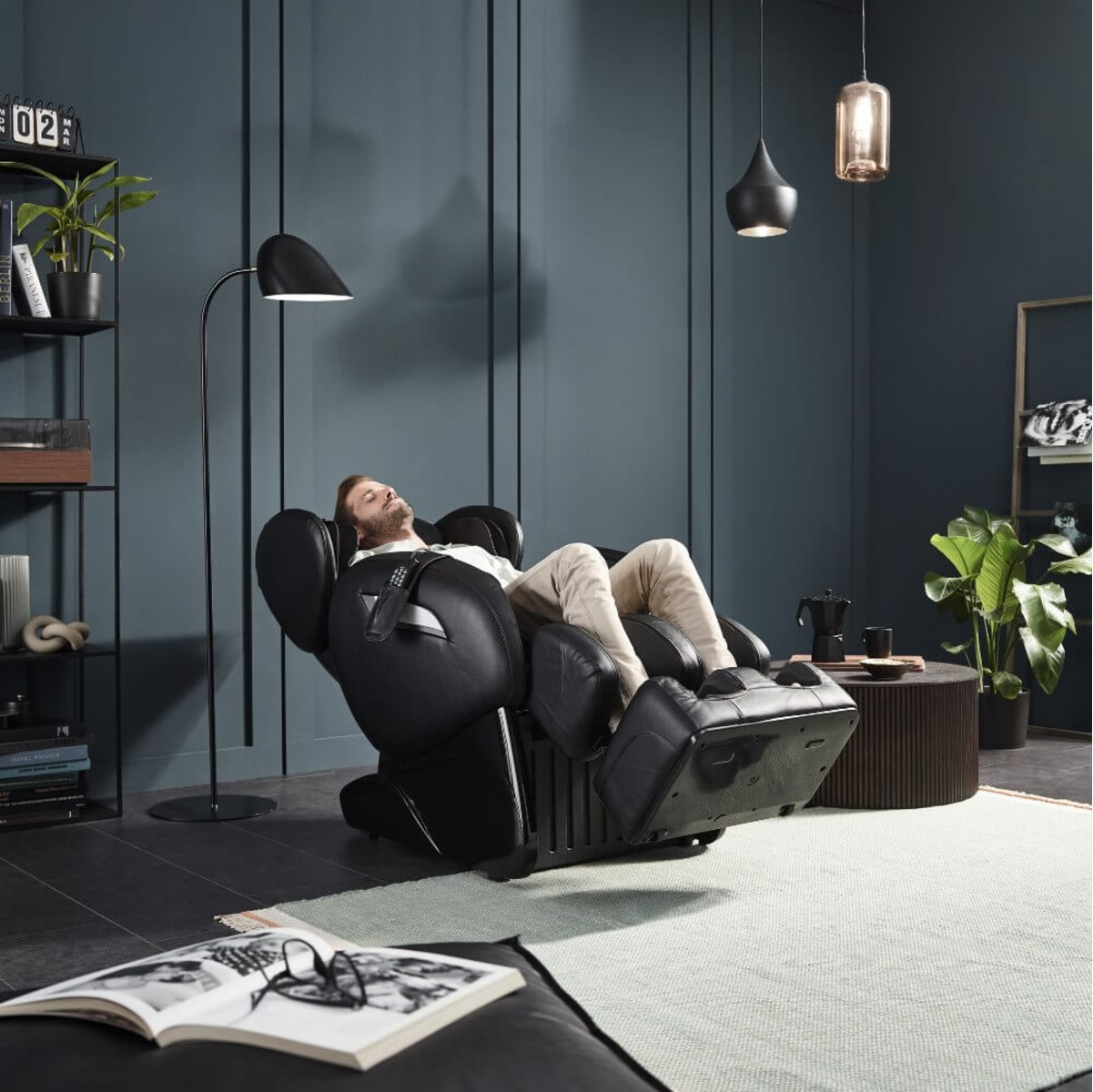 Mann liegt in schwarzem Massagesessel in modernem Wohnzimmer.