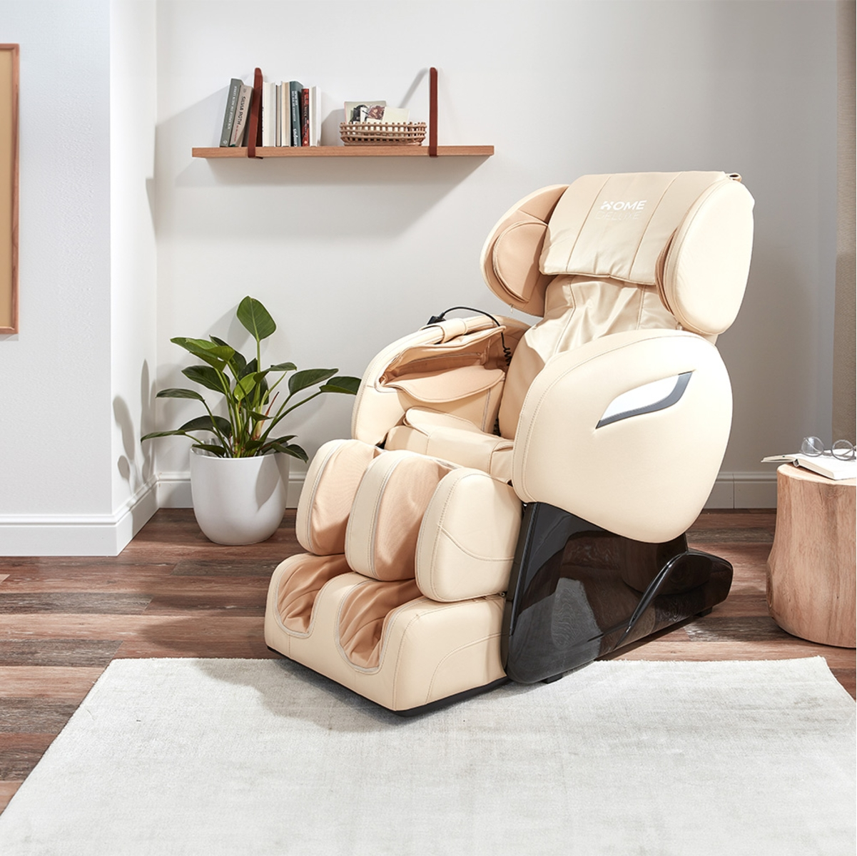 Beiger Massagesessel in einem Raum mit einer Pflanze und einem Holzregal mit Büchern.