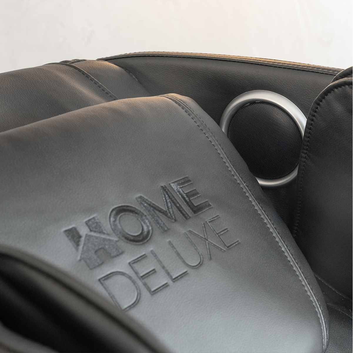 Nahaufnahme eines schwarzen Massage-Sessel-Kopfstütze mit den Worten 'HOME DELUXE' geprägt darauf.