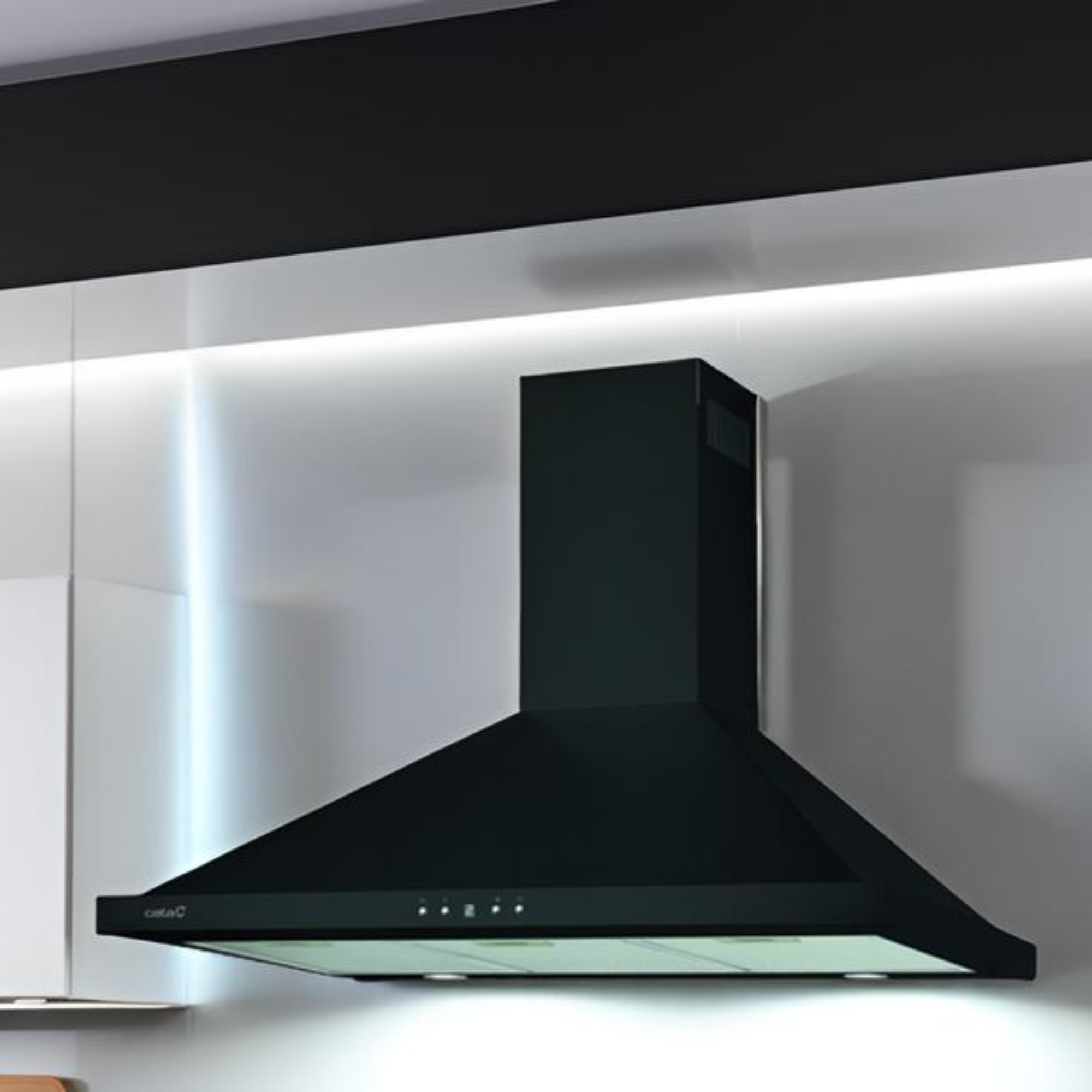Una campana extractora negra instalada en una cocina moderna con gabinetes blancos y negros.