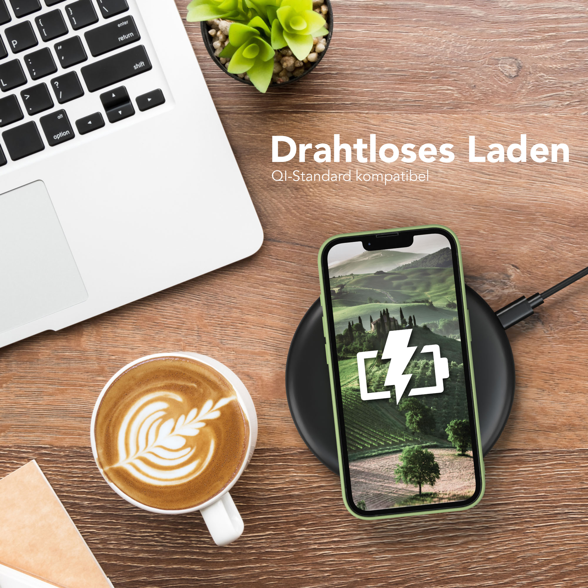 Telefon, das drahtlos auf einem Pad geladen wird, Kaffee mit Kunst, Laptop und eine Pflanze.