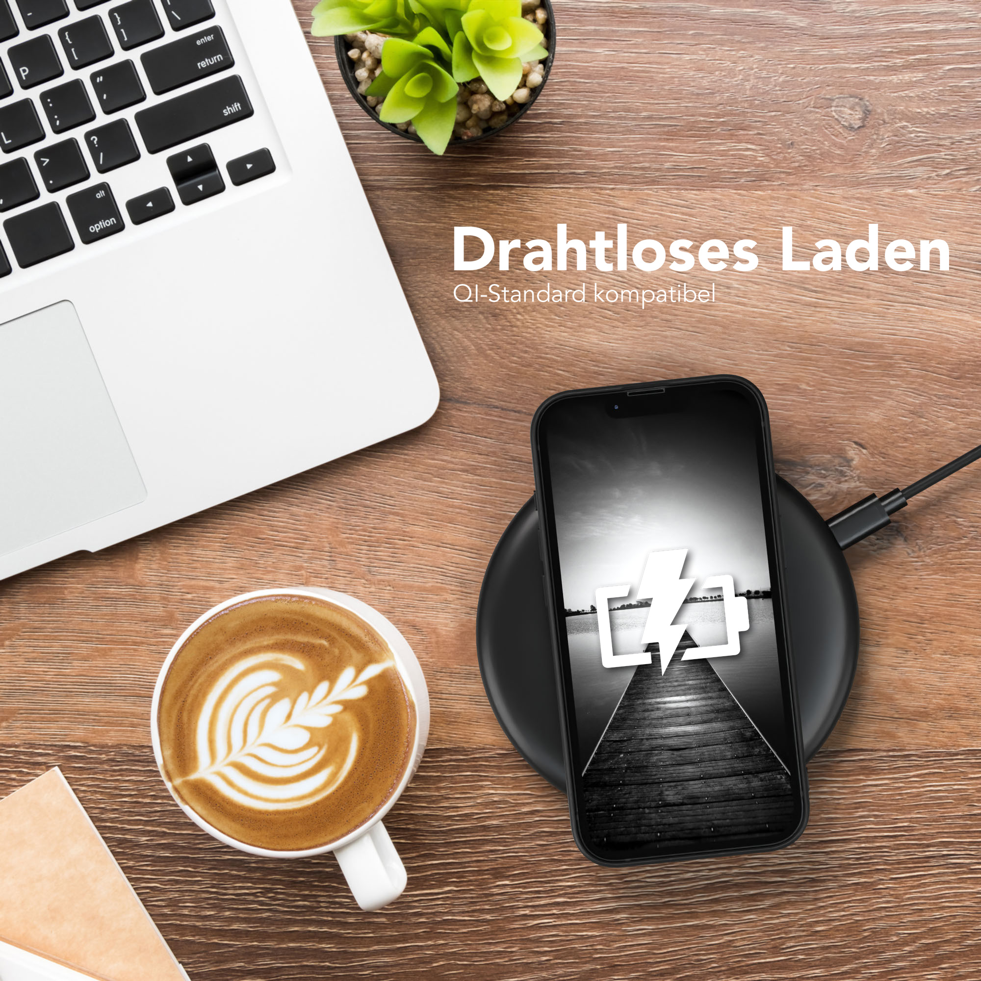 Ein Telefon, das drahtlos geladen wird, mit Kaffee und Laptop auf dem Holztisch. Eine kleine Pflanze im Hintergrund.