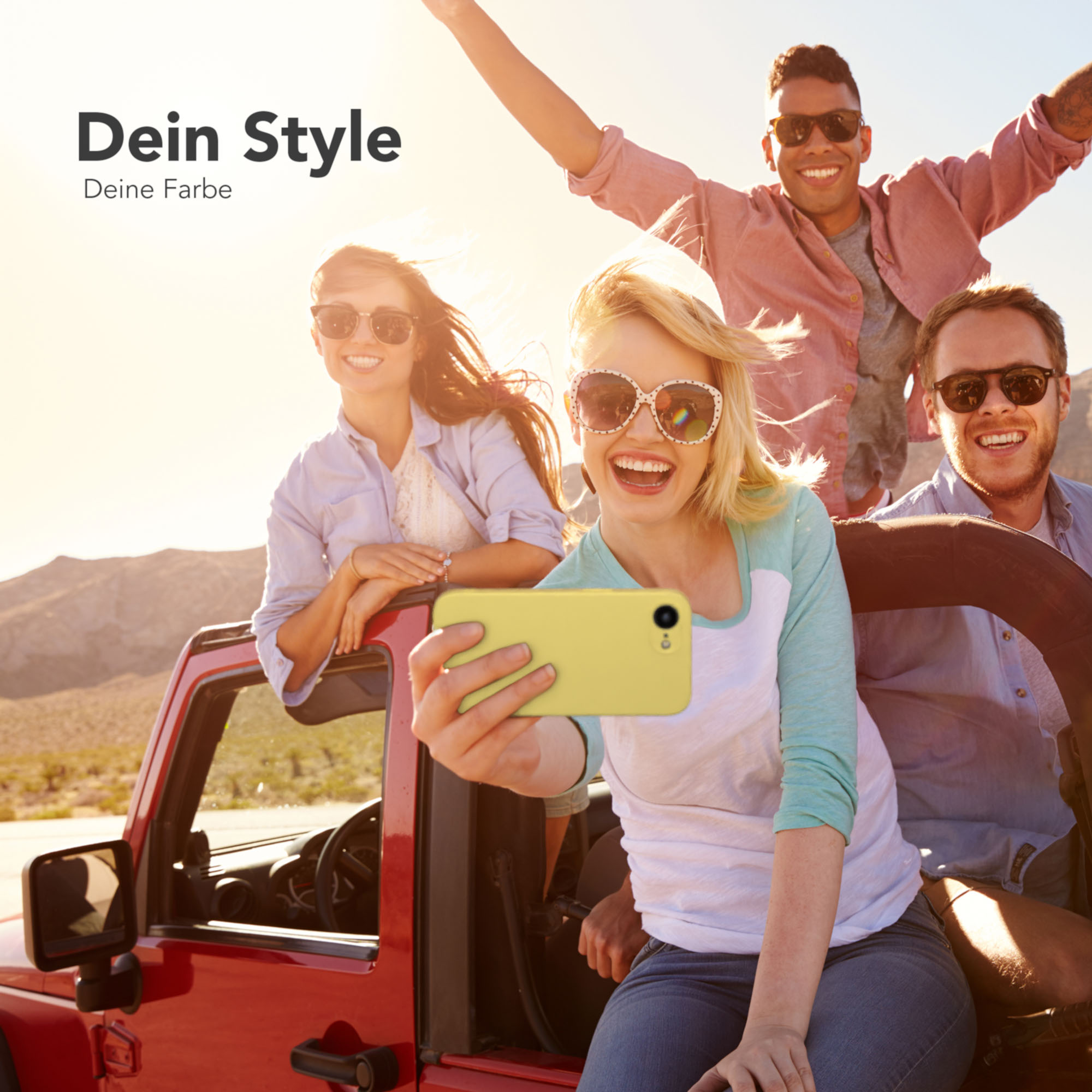 Vier lächelnde Personen in einem roten Jeep, die ein Selfie machen. Sie tragen Sonnenbrillen, sonnig draußen.