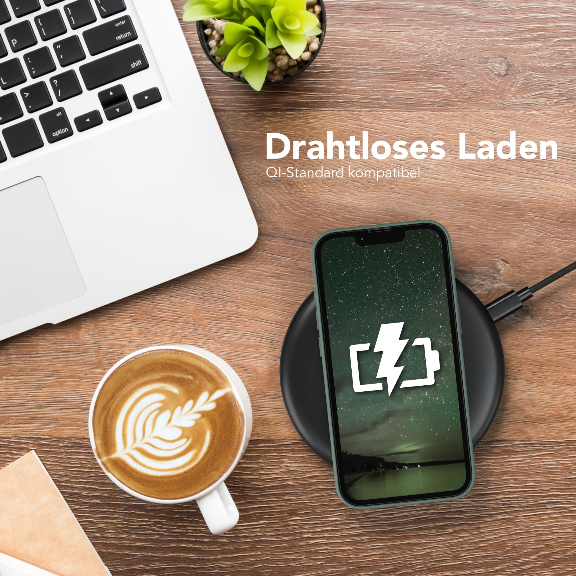 Telefon, das auf einem schwarzen Pad neben einem Laptop und Kaffee auf einem Holztisch geladen wird.