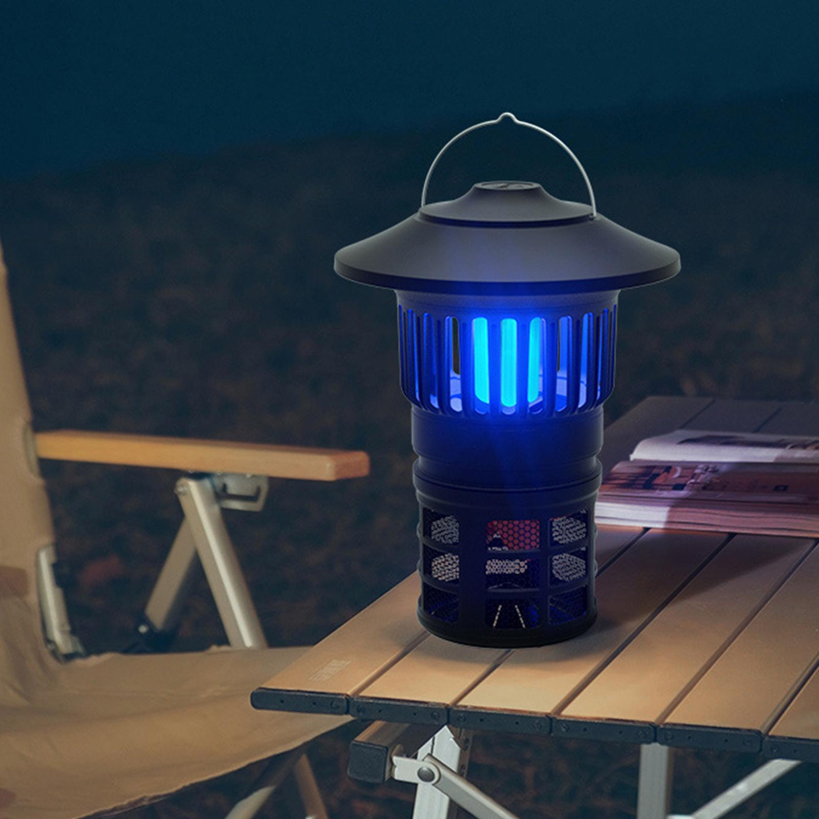 Eine schwarze Mückenvernichtungslampe steht nachts auf einem Tisch. Sie strahlt blaues Licht aus.