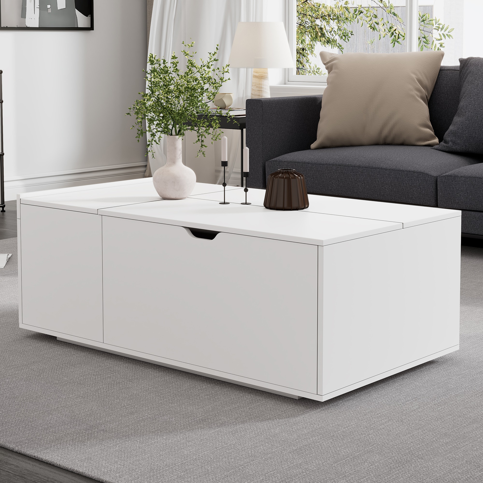 Weißer Couchtisch mit weißer Vase und Pflanzen. Mit Schublade und Sofa im Hintergrund.