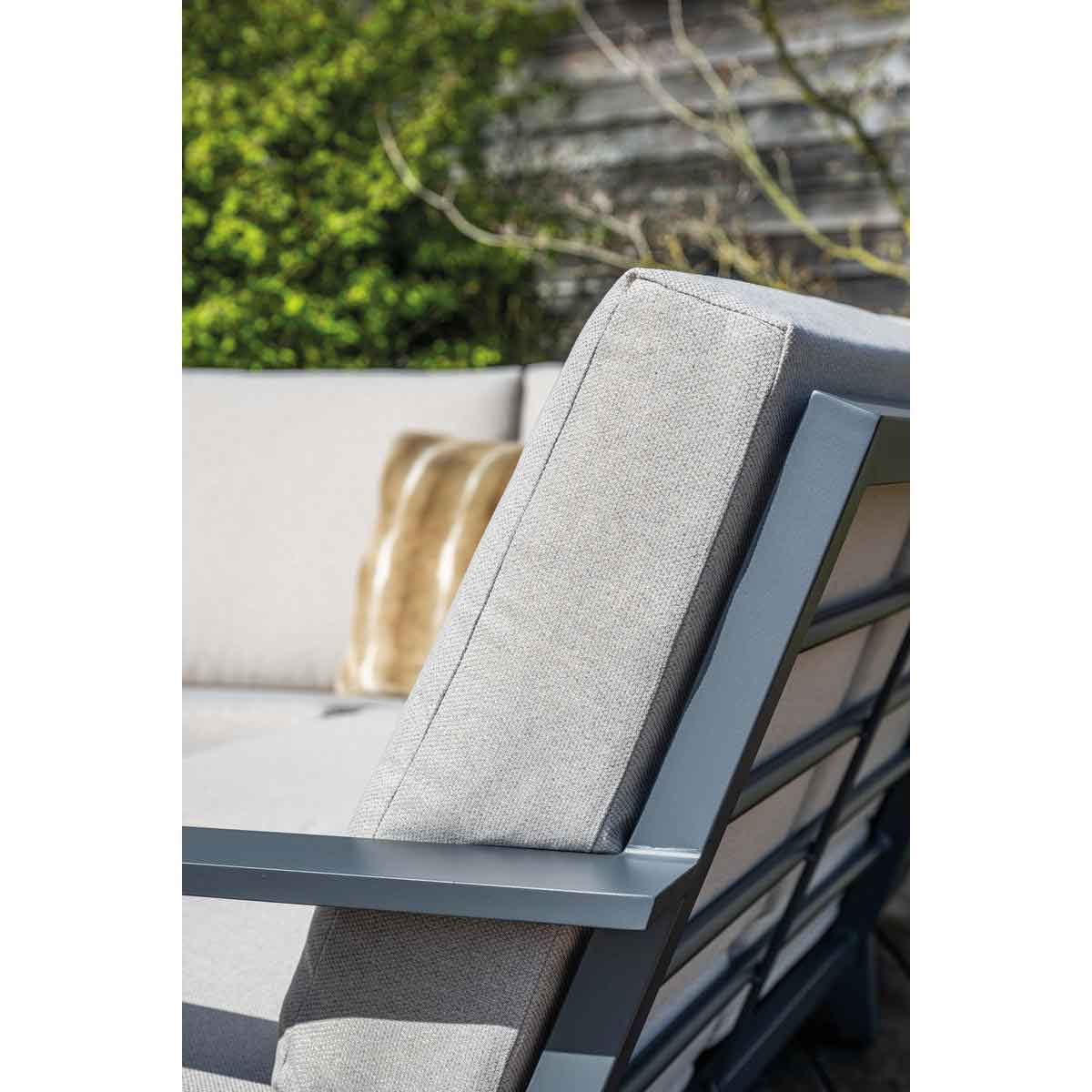 Close-up of outdoor sofa with gray cushions and a brown pillow, showing the back.