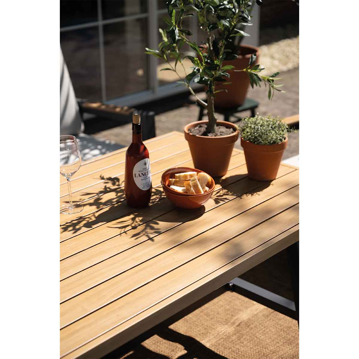 Tafelsetting met eten, drinken en planten. De tafel is van hout met bruine kleur.