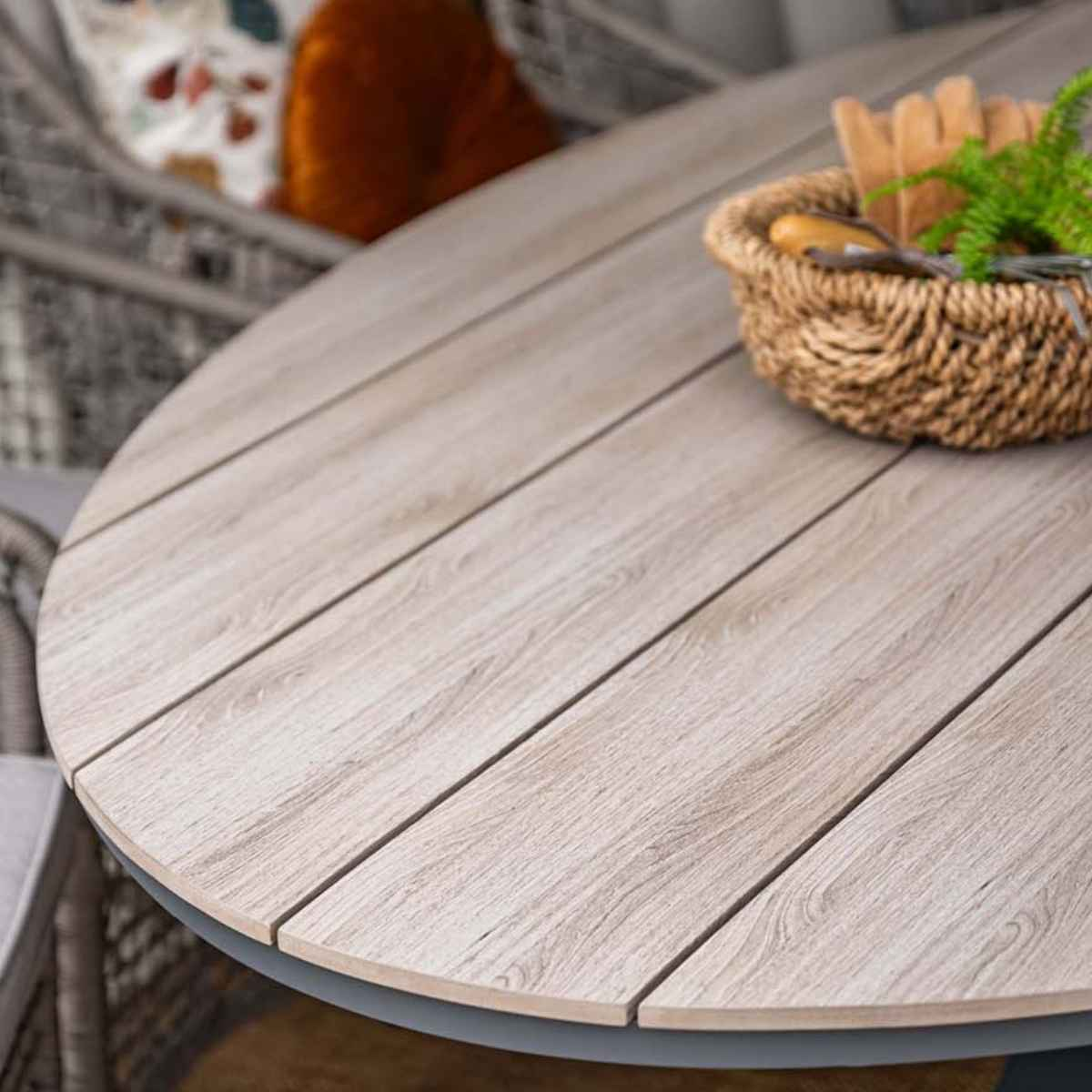 Tafeldetail: licht houten blad met grijze rand. Gevlochten mand met keukengerei.
