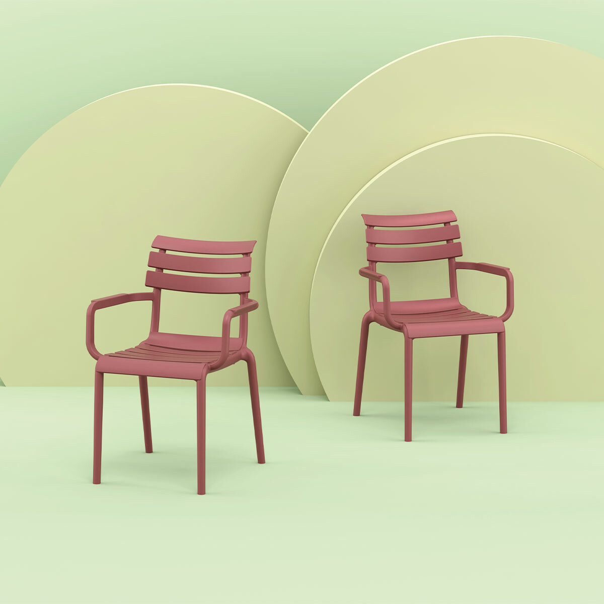 Twee roze stoelen met armleuningen. Op een lichtgroene achtergrond met cirkelvormen.