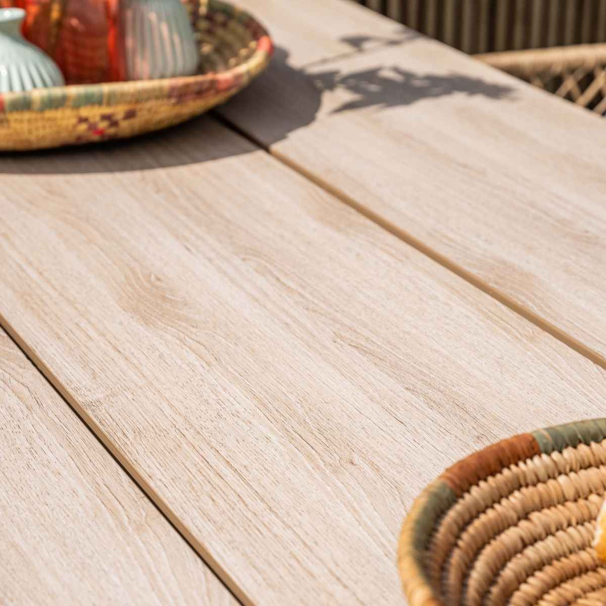 Close-up of a wooden table. Shows the wood grain, and a woven basket in the corner.