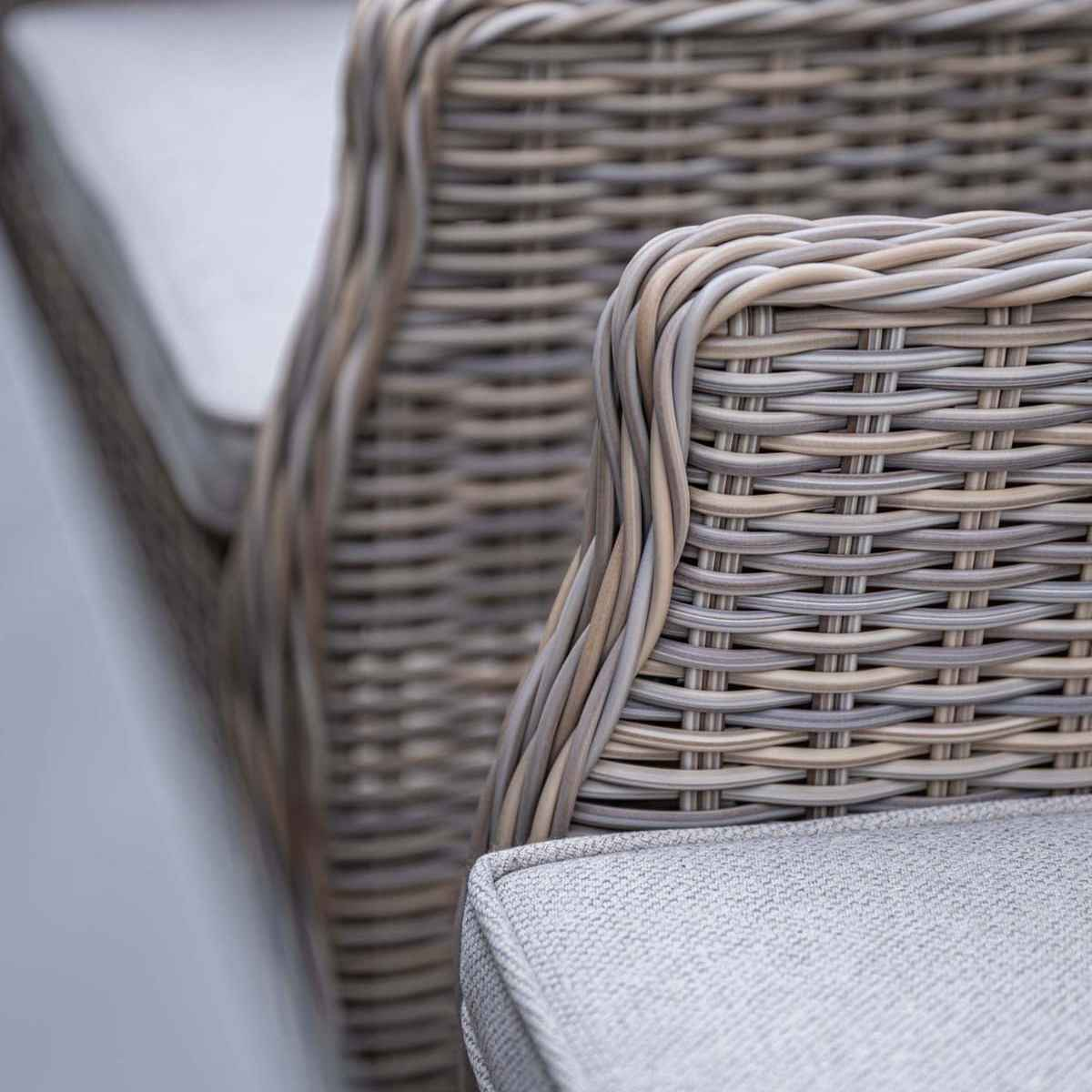 Close-up of the back of a woven chair with gray cushions. The weave pattern is visible.