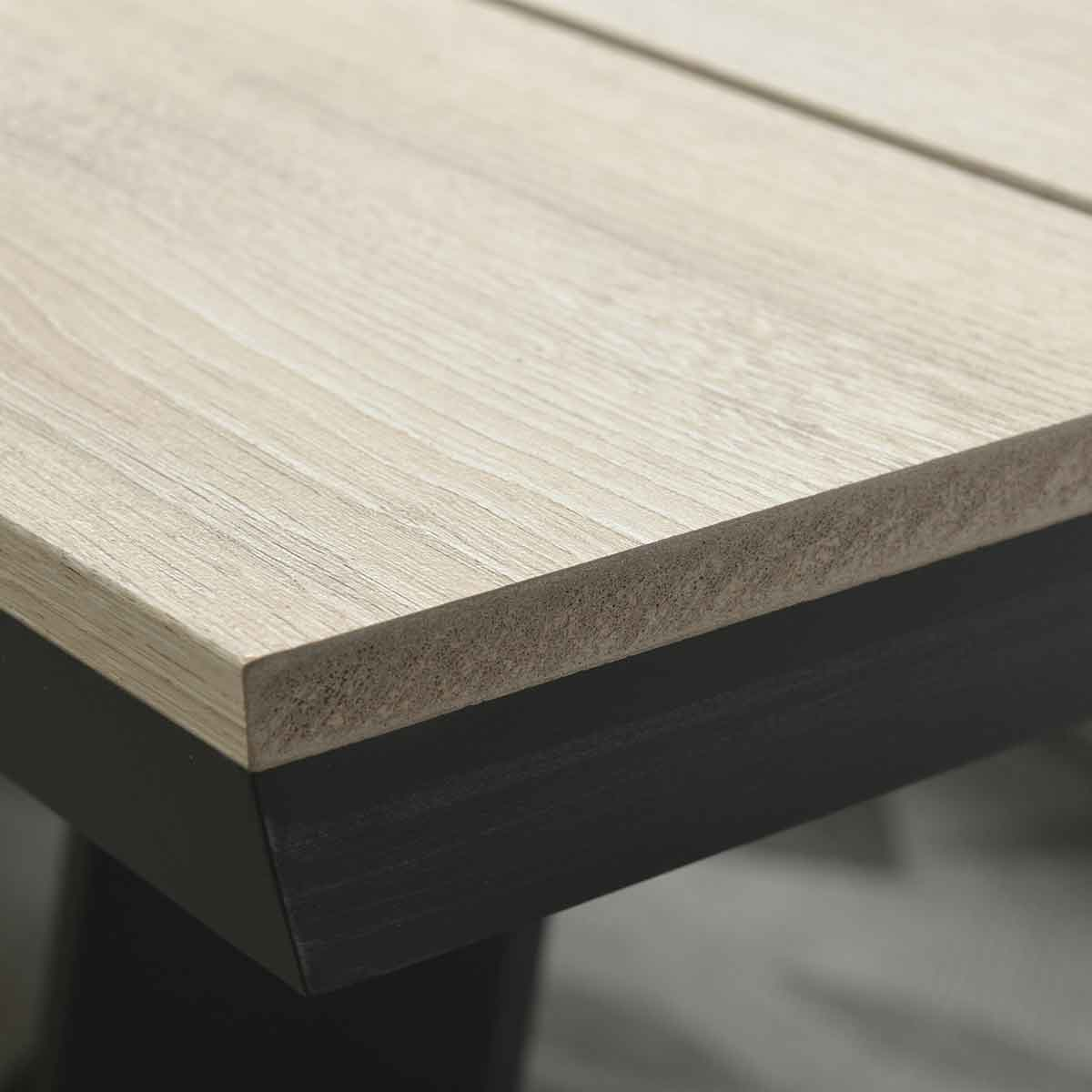 Gros plan sur un dessus de table en bois clair avec une bordure noire. Le bord est visible.