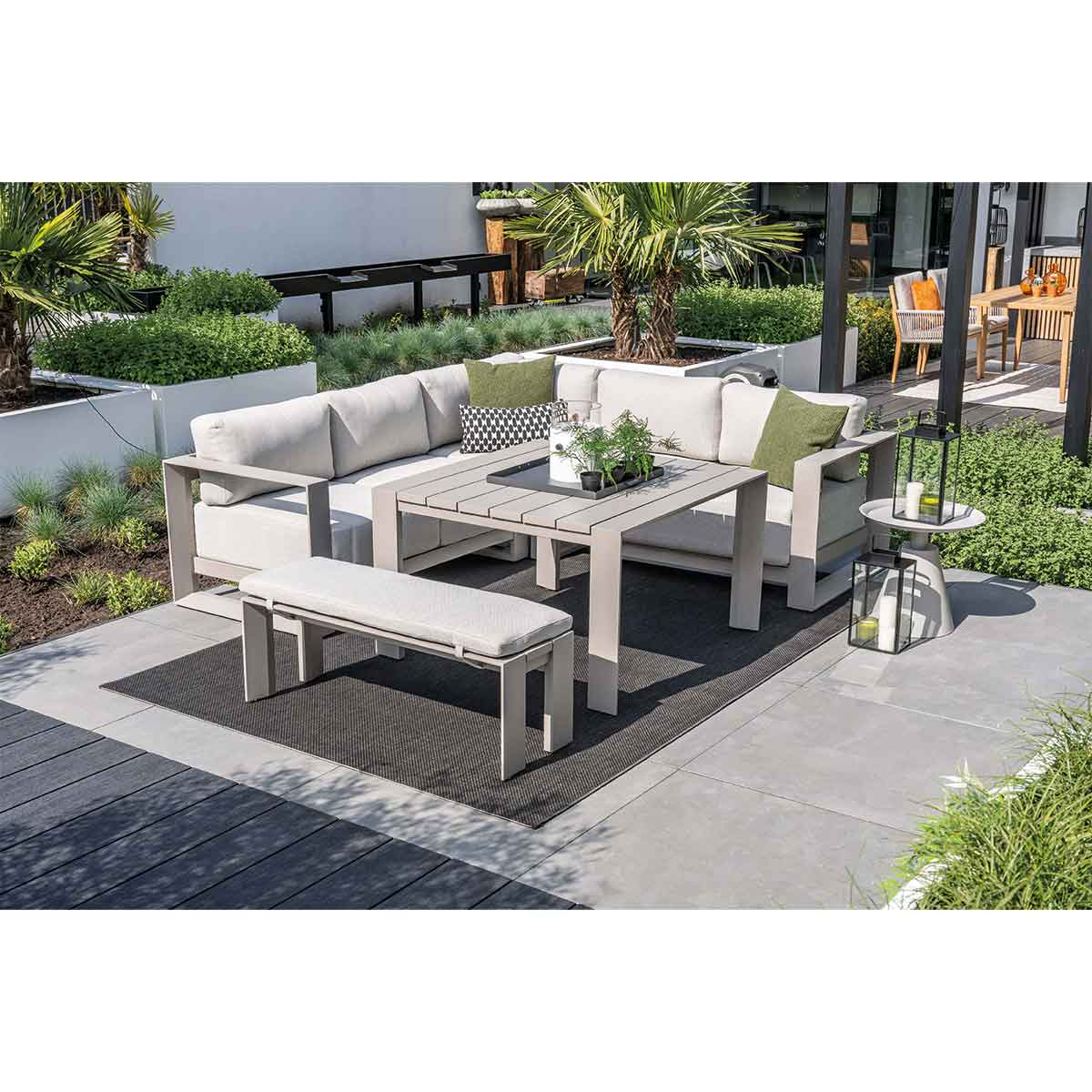 Buiten zithoek met lichtgekleurde meubels. Tafel, bank en sofa staan op een grijs oppervlak.