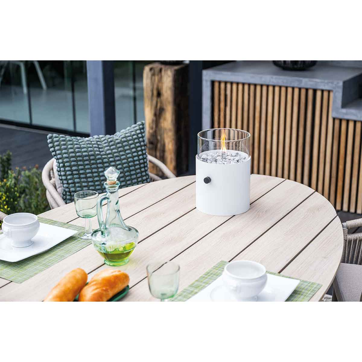A table set for dining outdoors. Includes food, drinks, and a small flame in a glass container.