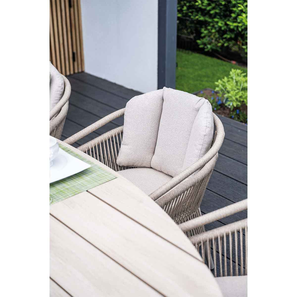 Close-up of chair with cushions and table. The chair is light beige with rope-like details.