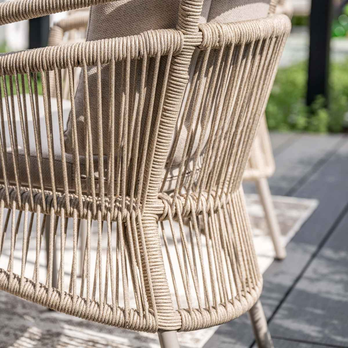 Close-up of a beige woven chair back. Vertical lines form the back. A light cushion is visible.