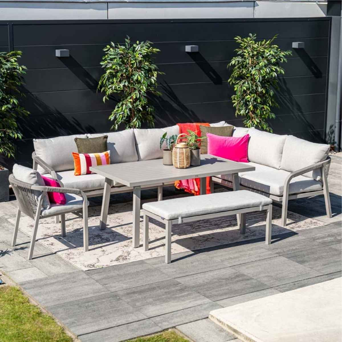 Ensemble de salle à manger d'extérieur avec une table grise, des chaises et un banc, le tout sur un patio.