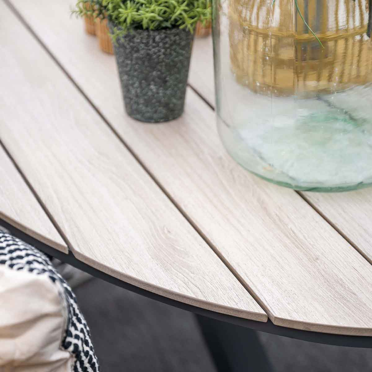 Close up of a wooden table with a plant and a glass jug on it. Black edge.