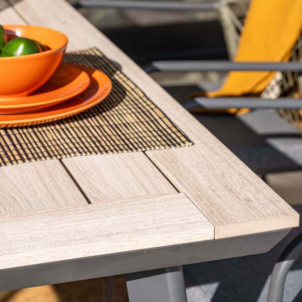 Close up of a table with plates, a mat, and an orange bowl with limes.