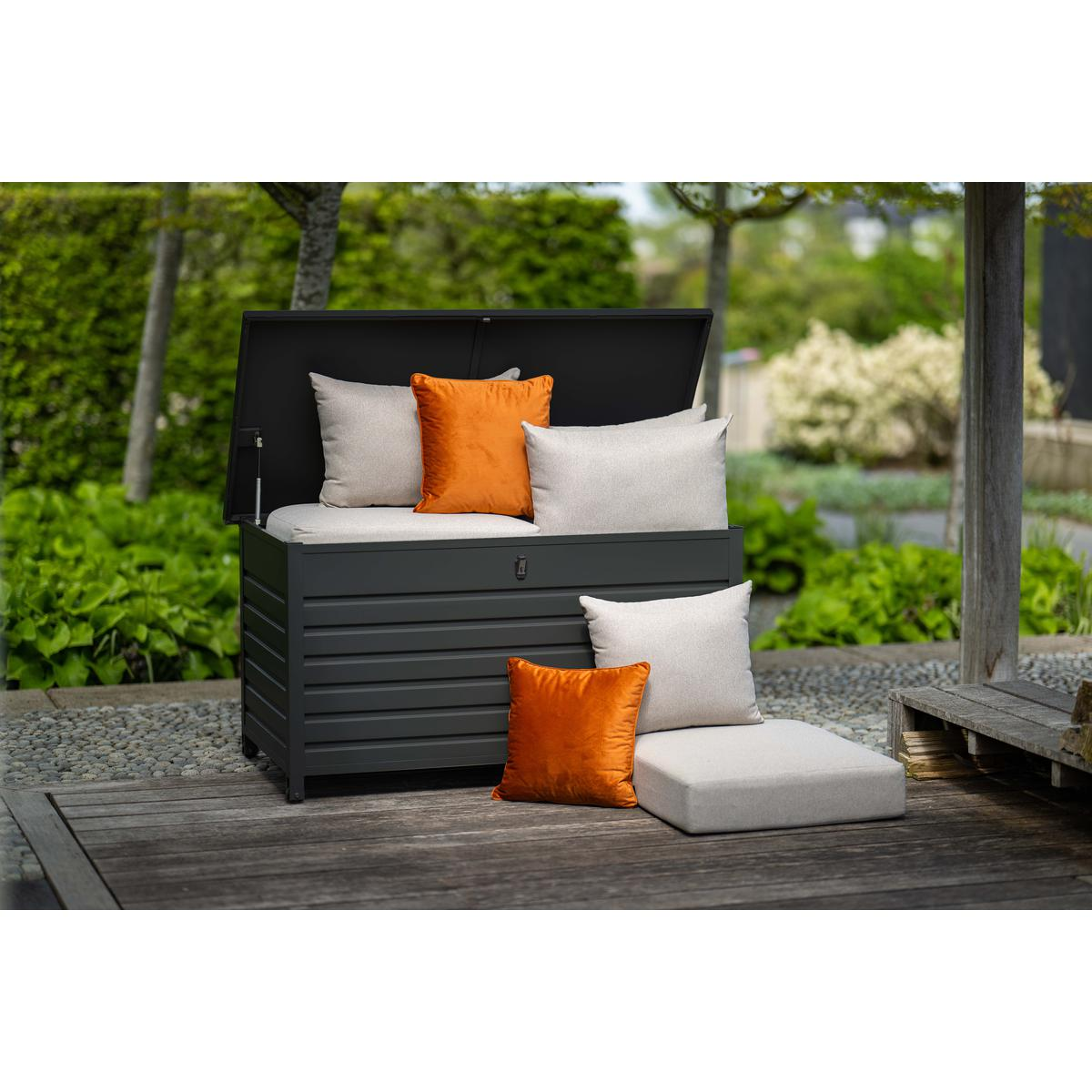 Coffre de rangement extérieur sur une terrasse en bois, avec oreillers et coussins.
