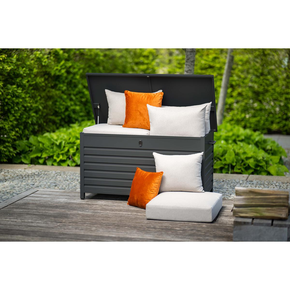 Coffre de rangement extérieur avec oreillers et coussins, sur une terrasse en bois.