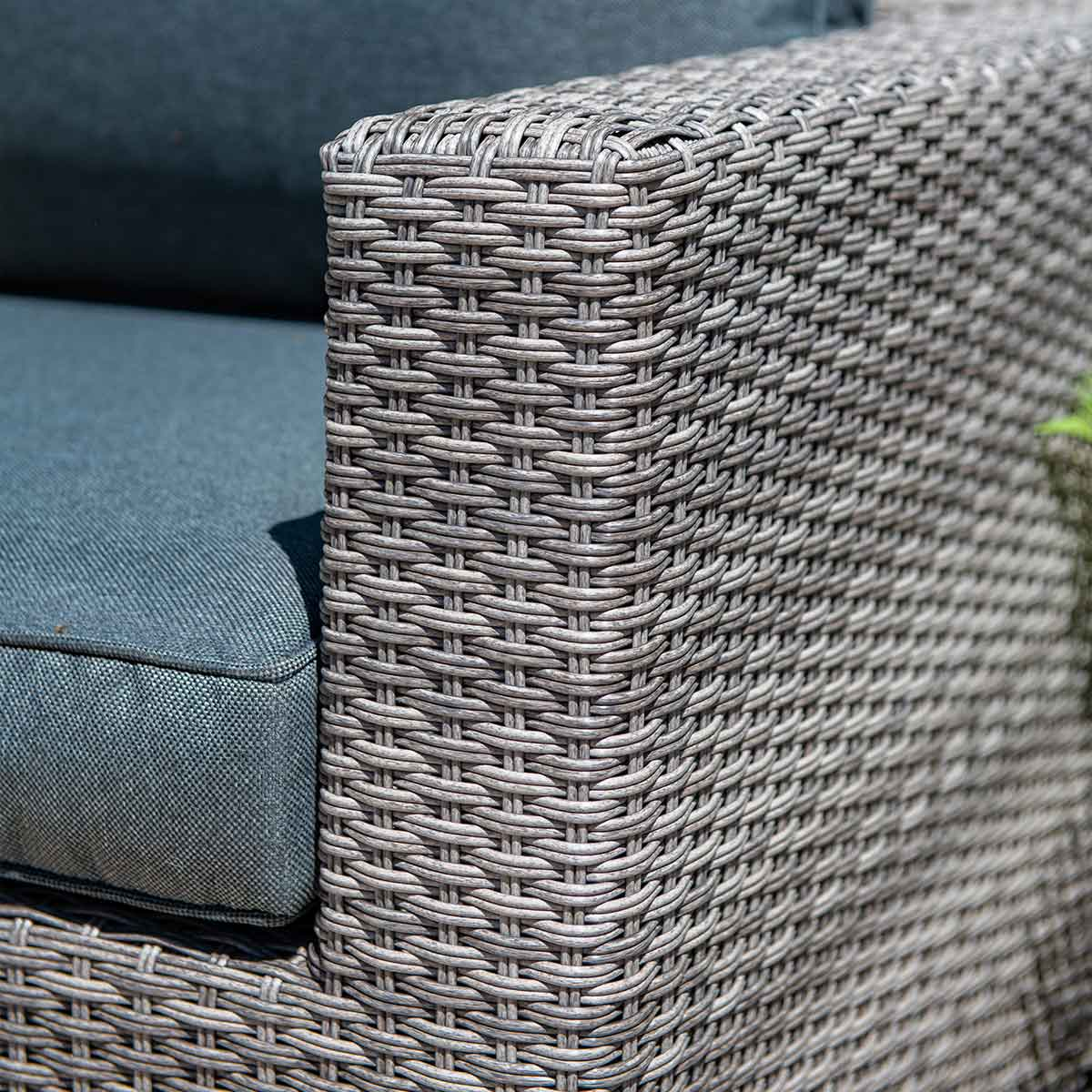 Close-up van rotan stoeldetail: grijze geweven textuur, kussen en kussen met grijze en mint stoffen.