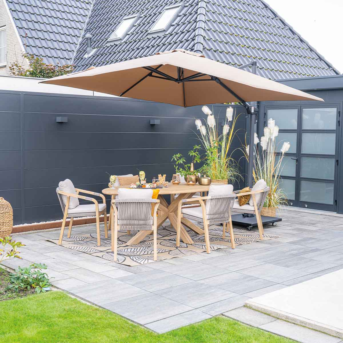 Un ensemble de patio sous un grand parasol. Table, chaises et plantes en arrière-plan.
