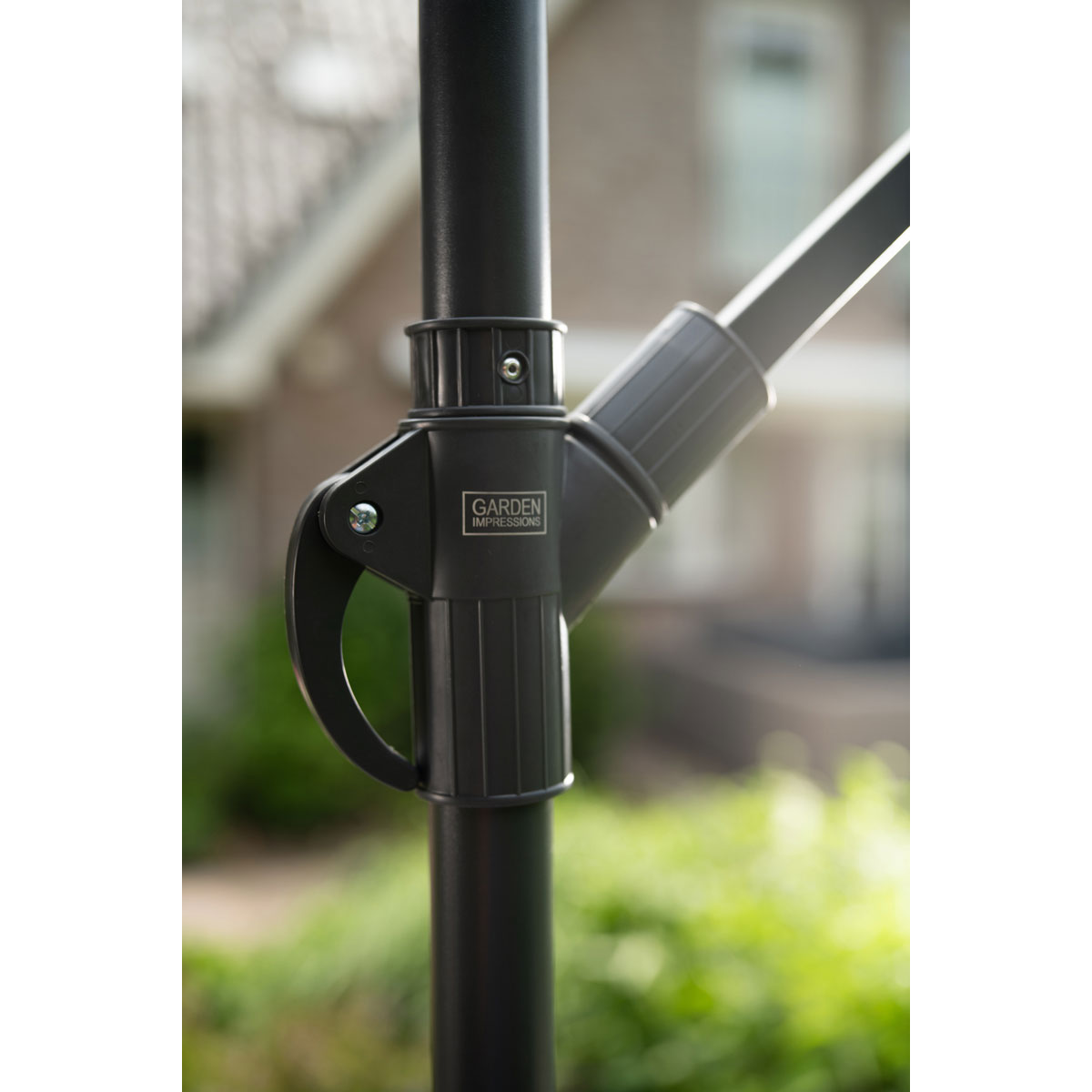 Gros plan sur un mécanisme de parapluie noir avec le texte 'GARDEN IMPRESSIONS' sur un poteau noir.